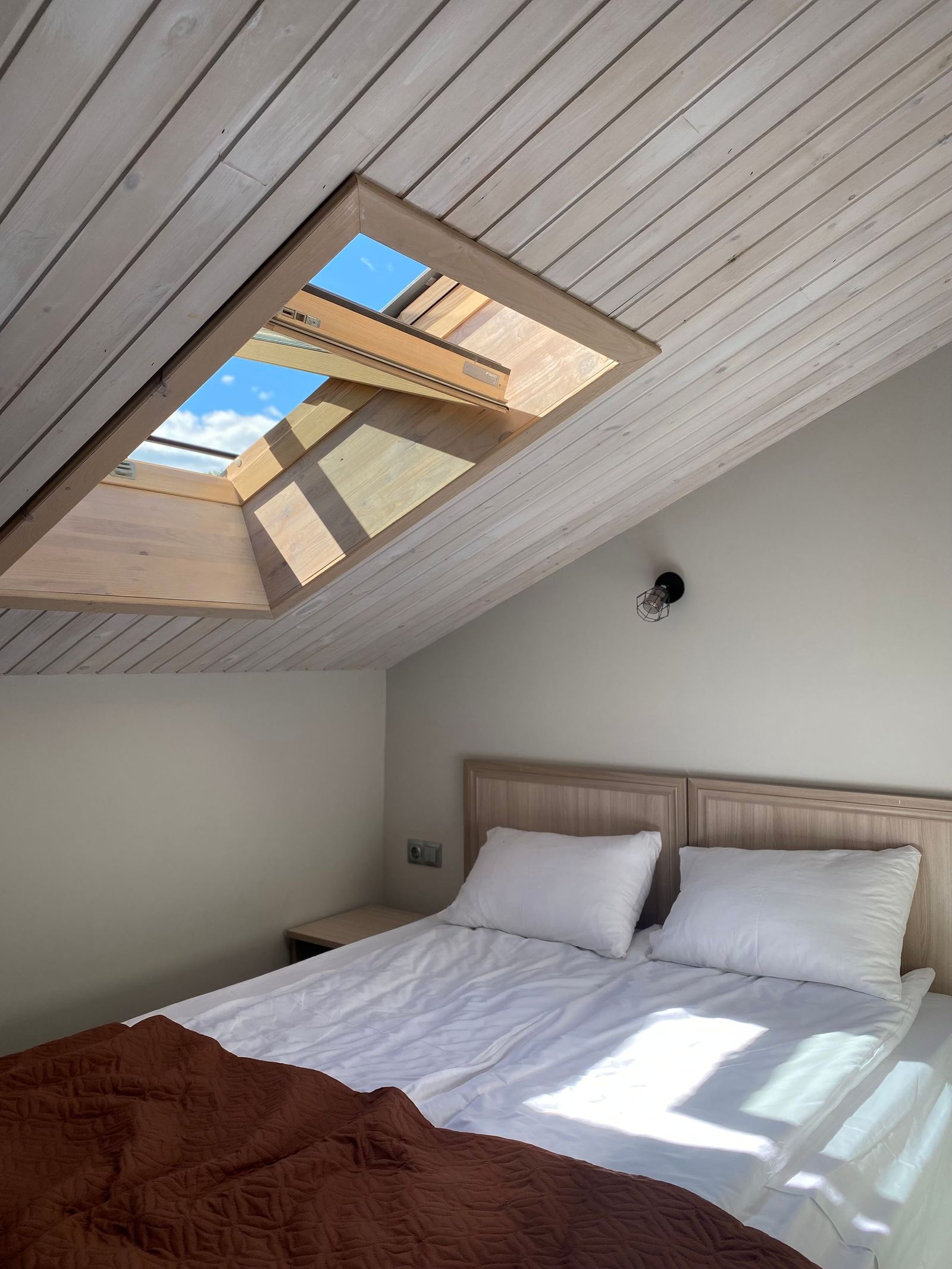 Chambre sous les combles éclairée par une fenêtre de toit ouverte